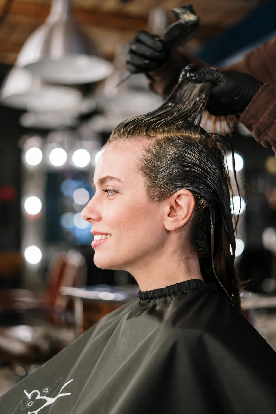 A smiling salon guest receiving a hair color service